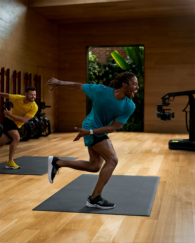 Instructores de Apple Fitness+ dirigen una sesión frente a cámaras en un estudio de grabación. 