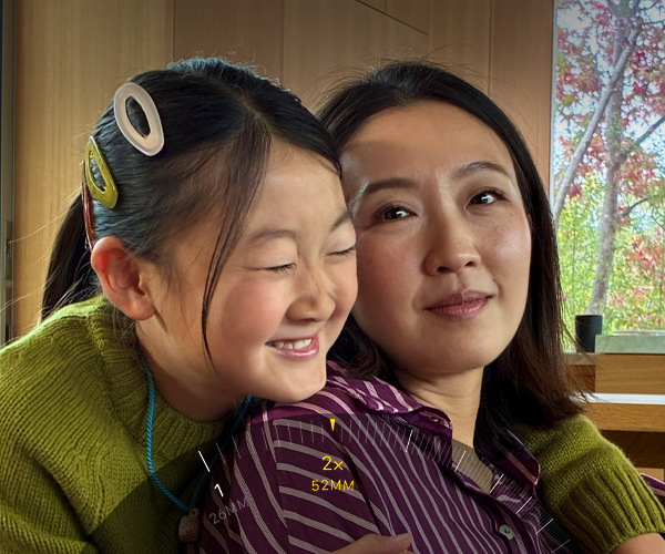 2x Telephoto feature in use, zooming in on two people hugging
