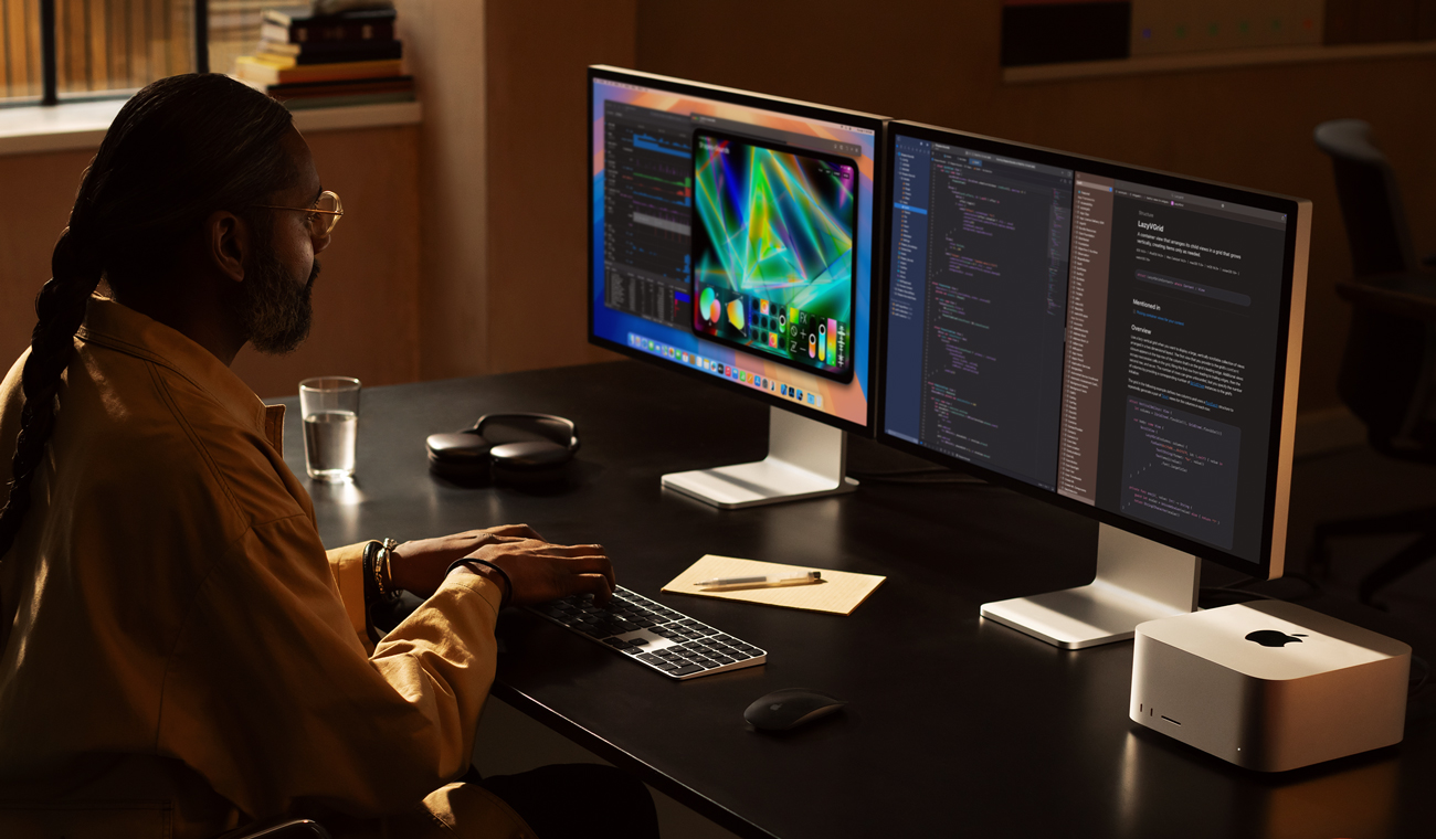 A person is sitting at a desk with three Studio Displays side by side, Mac Studio is on the desk, all screens show medical imaging software applications