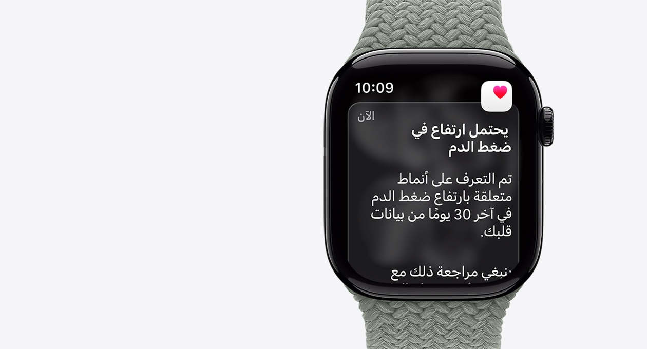 Apple Watch Series 11، لون طبيعي، إطار ألومنيوم، إشعار ارتفاع محتمل لضغط الدم، قلب وردي في صندوق أبيض، الجزء الخارجي الأيمن، التاج الرقمي‏، حزام Loop أحادي مَجدول بلون رمادي مخضر