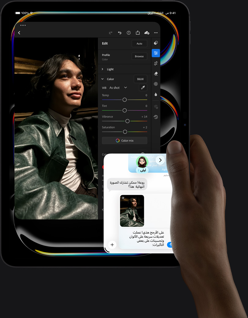جهاز iPad Pro، الجزء الأمامي الخارجي، الوضع العمودي، لون أسود فلكي، يد يمنى تحمل الجهاز، شاشة تعرض تطبيقاً لتعديل الصور مع صورة لشخص يرتدي زياً أزرق، وأدوات التعديل وخياراته في القائمة اليمنى، وفي الجزء السفلي الأيمن من الشاشة تبدو محادثة iMessage جارية بين المستخدم وشخص آخر لمراجعة الصورة
