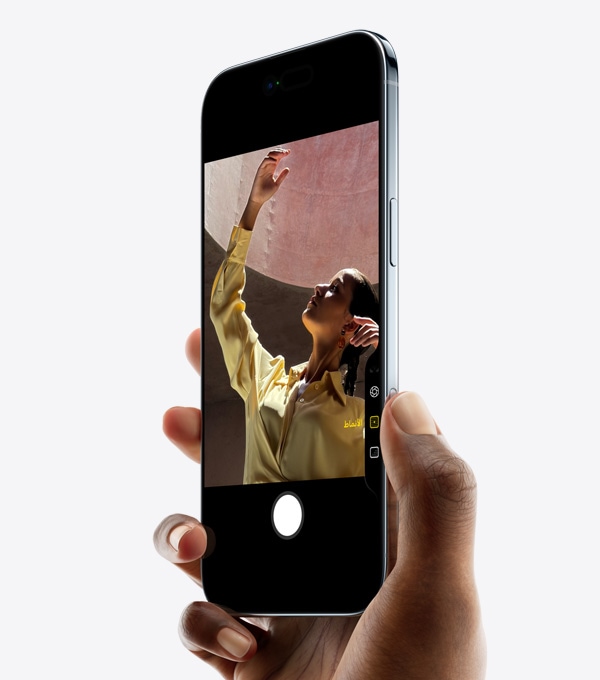 صورة ليد تحمل iPhone Air وإصبع الإبهام على زر التحكم في الكاميرا، الجزء الأمامي الخارجي، الجزء الجانبي الخارجي، تصميم نحيف، Dynamic Island، الزر الجانبي