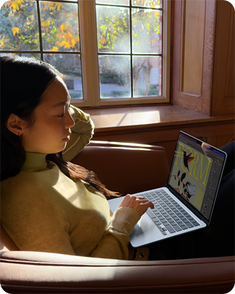 A person sitting in a chair using their MacBook Air