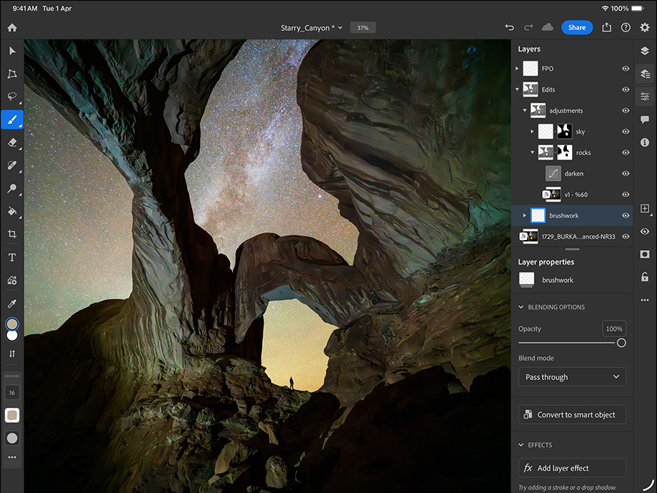 iPad Pro, front exterior, landscape orientation, space black colour, rounded corners, black display bezel, display showing a photograph being edited of a canyon and a star-filled night sky, at right, editing layers, tools and effects visible including brushwork, adjustments and others