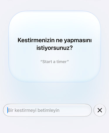 Ekranda bir Apple Intelligence isteği ve kullanıcıdan gelen yanıt gösteriliyor. Kestirme özelliği kullanıcıya What do you want your shortcut to do? diye soruyor ve kullanıcı da When I’m leaving work message Pedro I’m on my way with my ETA cevabını veriyor.