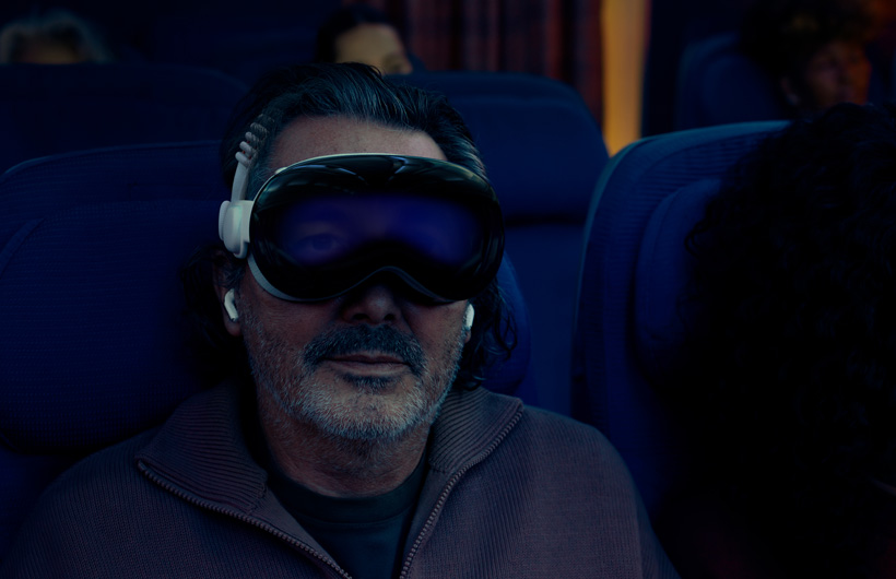 Personne assise dans un avion portant l’Apple Vision Pro avec le bandeau tissé à sangle double