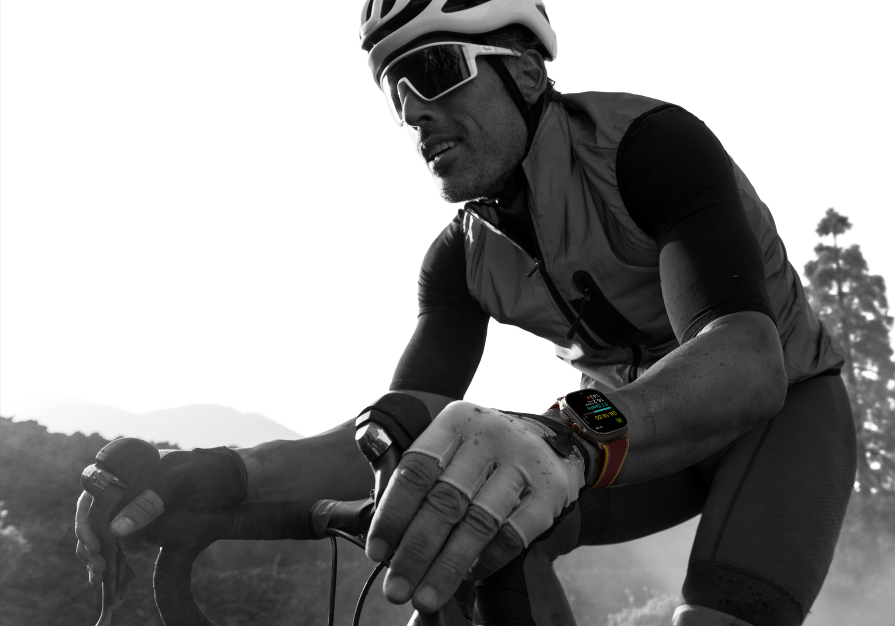A person riding a road bike while wearing Apple Watch Ultra 4, screen shows cycling metrics