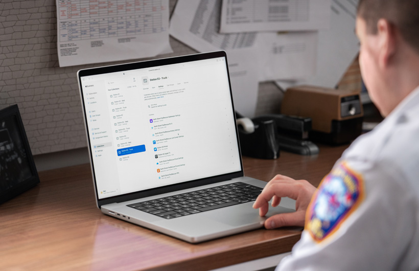 Comandante da corporação de bombeiros, sentado no escritório, a usar um MacBook com o Apple Business Essentials aberto no ecrã
