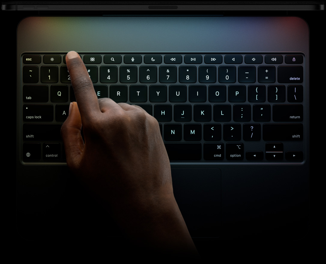 iPad Pro, landscape orientation, space black color, top edge profile, attached to Magic Keyboard, front exterior, landscape orientation, black color backlit keys, dedicated function key row, escape, tab, caps lock, shift, control, option, shift, delete, return, inverted-T arrow keys, built-in trackpad